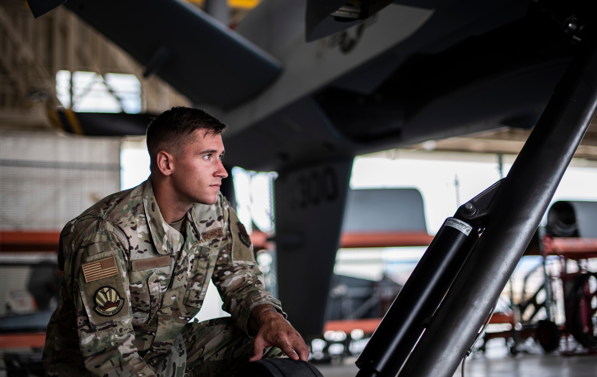 Senior Airman Levi looks up into the distance while under an MQ-9 Reaper.