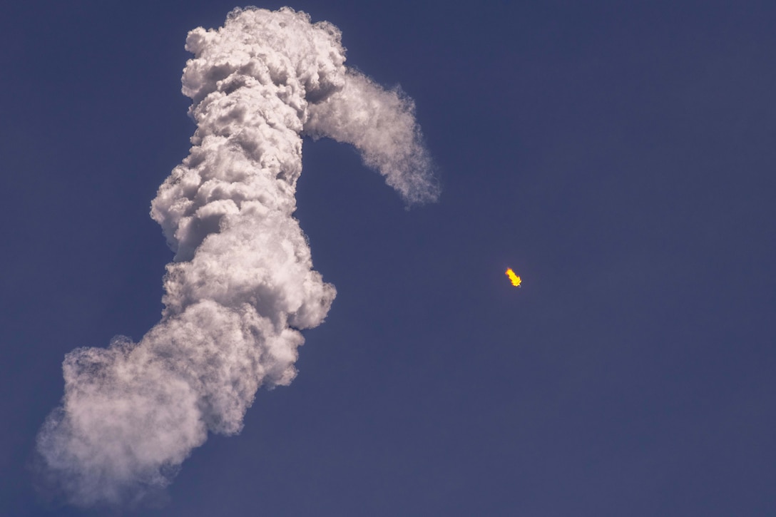 A satellite launches leaving an arc of thick smoke.