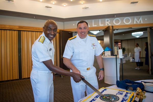 Rear Adm. Stephen Barnett, outgoing commander, from Columbia, Tennessee, and Rear Adm. Brad Collins, new commander, Navy Region Northwest cut a ceremonial cake after a change of command ceremony at Naval Base Kitsap-Bangor June 18.