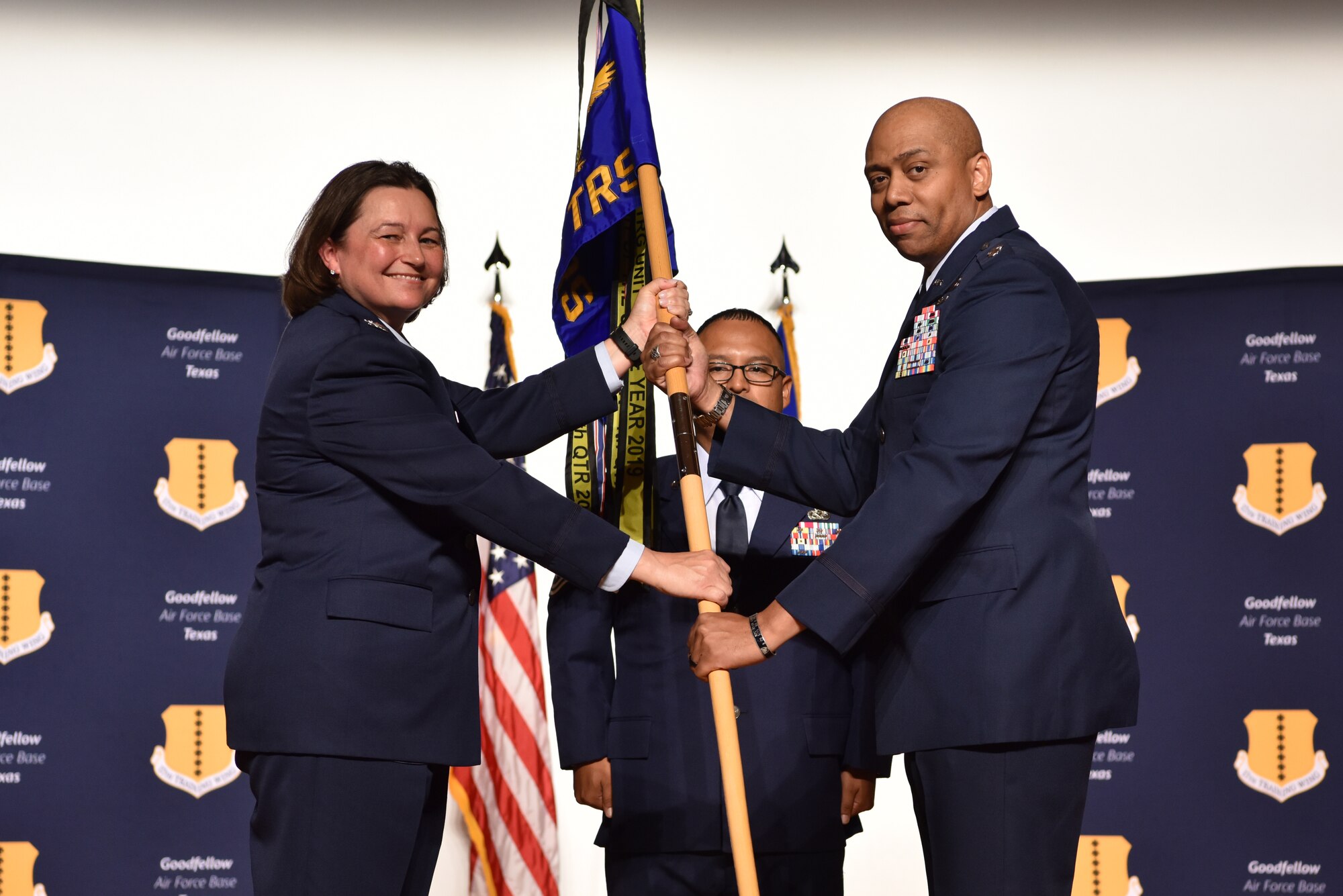 U.S. Air Force Col. Angelina Maguinness, 17th Training Group commander, passes the guidon to Lt. Col. Erwin Mason, incoming 316th Training Squadron commander, during the change of command ceremony at the Base Theater on Goodfellow Air Force Base, Texas, June 18, 2021. Mason was previously the chief for the Middle East and Africa Division at the U.S. Cyber Command in Maryland. (U.S. Air Force photo by 2nd Lt. Steve Garrett)