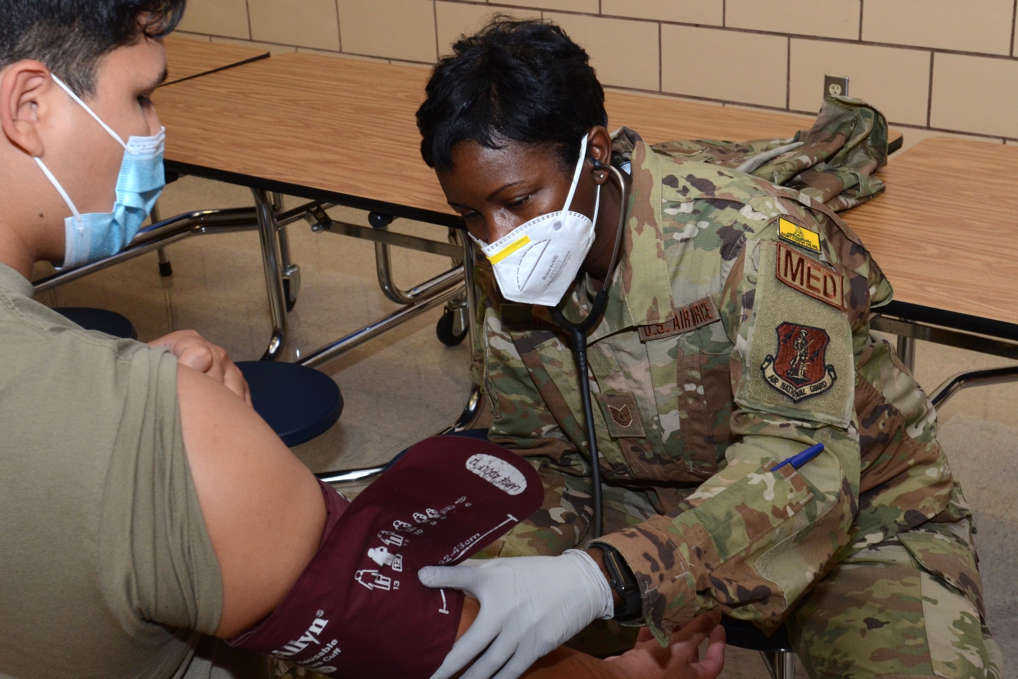 U.S. Air Force Tech. Sgt. Barbara Woods, assigned to the 169th Fighter Wing, McEntire Joint National Guard Base, South Carolina, supports Operation Healthy Delta, a Department of Defense sponsored Innovative Readiness Training program designed to provide military training opportunities by providing key services to local citizens. Woods is examining Senior Airman Ron Armaza, 162nd Wing for training purposes in the intake section at Massac County High School, Metropolis, Illinois June 16, 2021. (U.S. Air National Guard photo by Lt. Col. Jim St.Clair, 169th Fighter Wing Public Affairs)