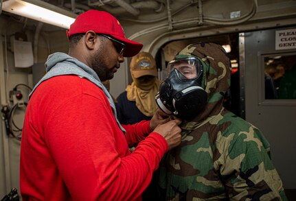 Aviation Maintenance Administrationman 1st Class Antonio Allen, left, from Forestville, Maryland, helps Aviation Electronics Technician 2nd Class Sara Hopkins, from Winston-Salem, North Carolina, don a joint service lightweight integrated suit technology during a general quarters training evolution aboard the Nimitz-class aircraft carrier USS Harry S. Truman (CVN 75) during Tailored Ship's Training Availability (TSTA) and Final Evaluation Problem (FEP).