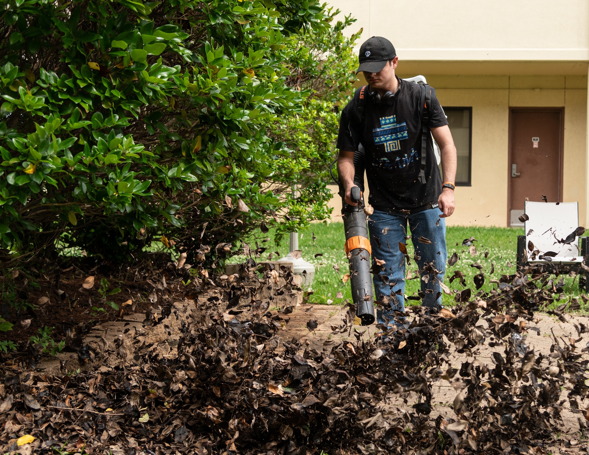 A Barksdale Airman blows away dead leaves during a campus clean-up at Barksdale Air Force Base, Louisiana, June 12, 2021. Dorm residents and senior leadership worked together to clean the Barksdale campus. (U.S. Air Force photo by Airman 1st Class William Pugh)