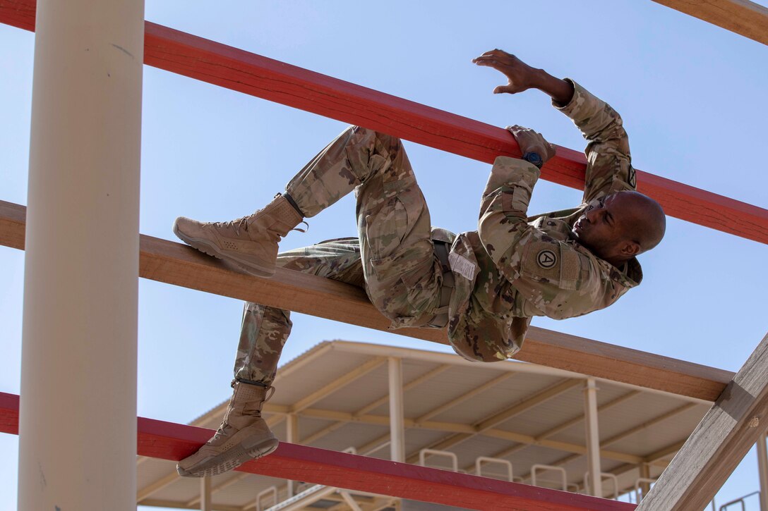 A soldier weaves through an obstacle of horizontal bars.