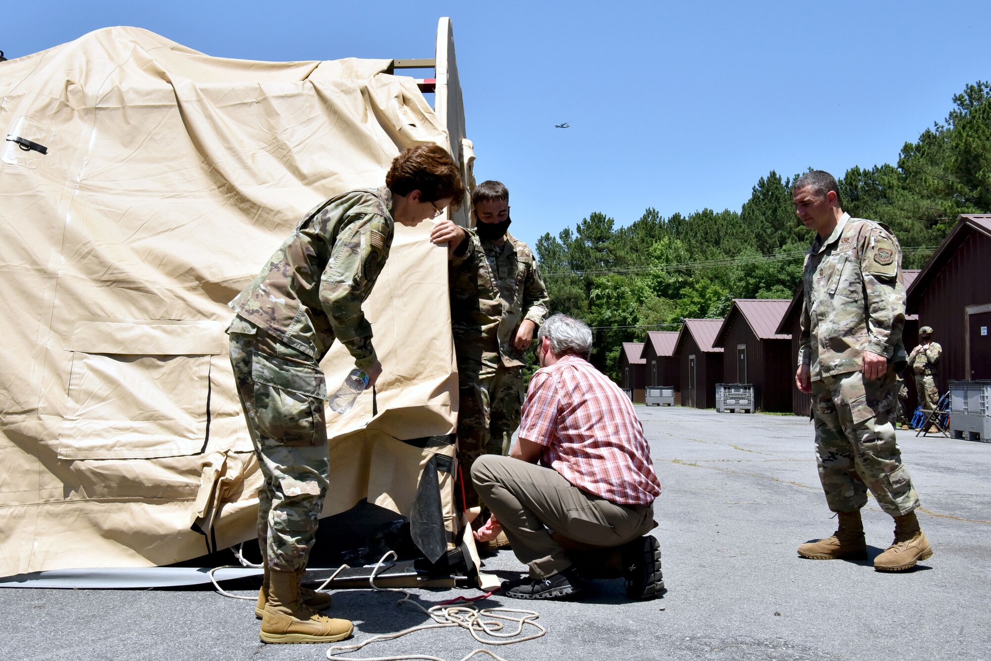 Gen. Jacqueline Van Ovost, Air Mobility Command commander, left, watches as AMC Civic Leaders learn to assemble a military shelter system