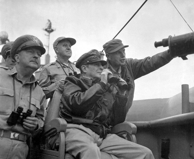 A group of military service members hold binoculars and observe war activity.