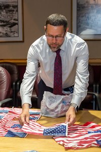 Norfolk Naval Shipyard Veteran Employee Readiness Group President Josh Wannemacher prepares U.S. Flags to be turned over to Sturtevant Funeral Home as part of their Retire Your Flag Program.