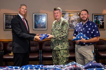 Norfolk Naval Shipyard Executive Officer Capt. Todd Nichols and Veteran Employee Readiness Group former President Nicholas Boyle turns over 217 U.S. Flags to Sturtevant Funeral Home Representative Robie Gardner in honor of Flag Day.