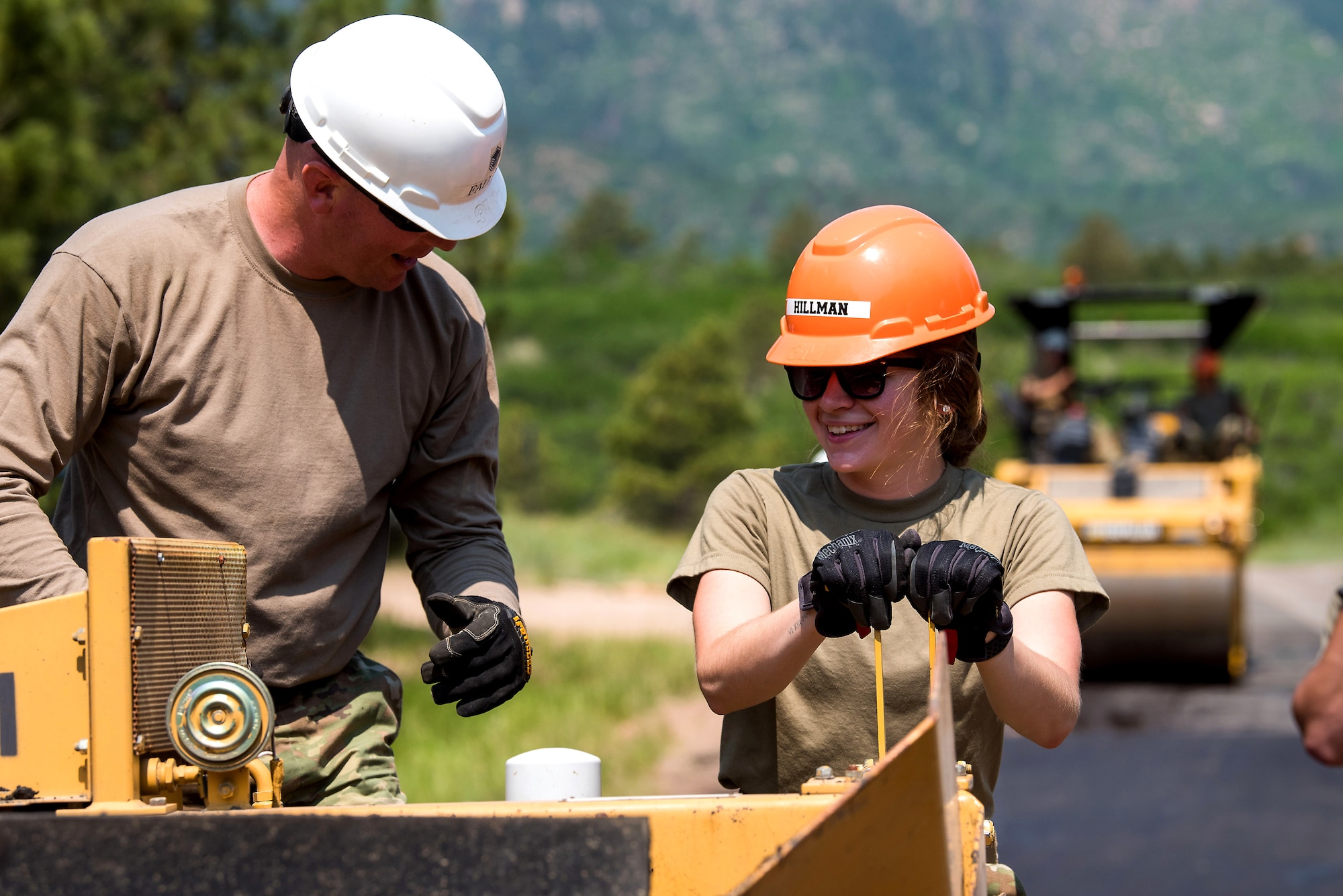 A U.S. Air Force Academy cadet and an enlisted mentor operate a paver on a road in Jack's Valley