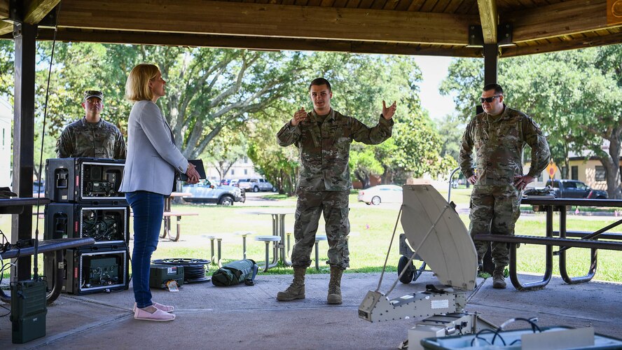 Senior Airman Michael Watkins, center, 2nd Communications Squadron radio frequency transmissions systems journeyman, briefs Lauren Barrett Knausenberger, left, Air Force chief information officer, on the capabilities of the single channel anti-jam man-portable (SCAMP) and PRC-150 high frequency radio systems at Barksdale Air Force Base, Louisiana, June 16, 2021. As the Air Force CIO, Knausenberger leads two directorates and supports 20,000 cyber operations and support personnel around the globe. (U.S. Air Force photo by Senior Airman Jacob B. Wrightsman)