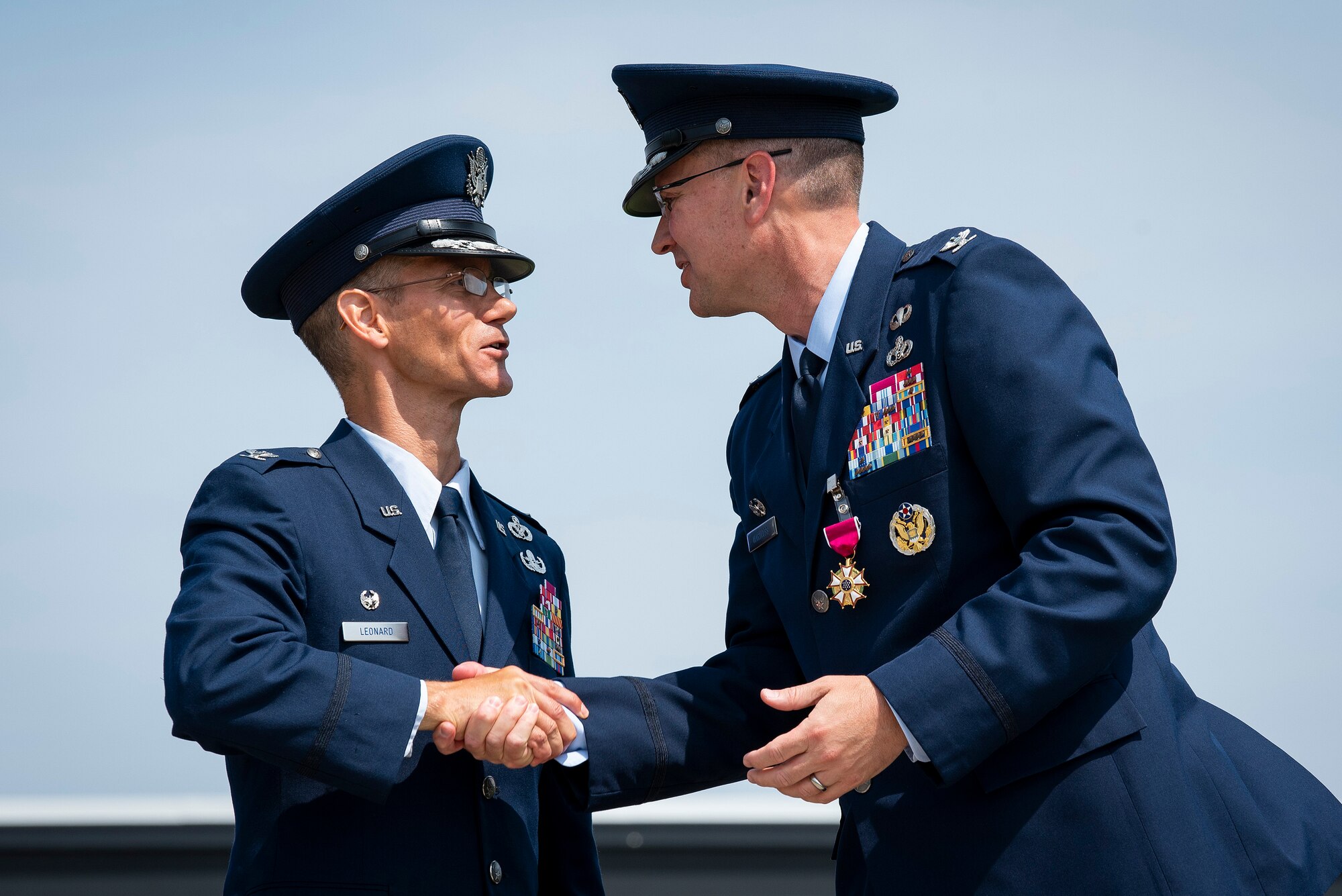 Col. Christopher Leonard, commander of the 10th Air Base Wing (left), shakes hands with his predecessor, Col. Brian Hartless after the wing's change of command ceremony, June 18, 2021.