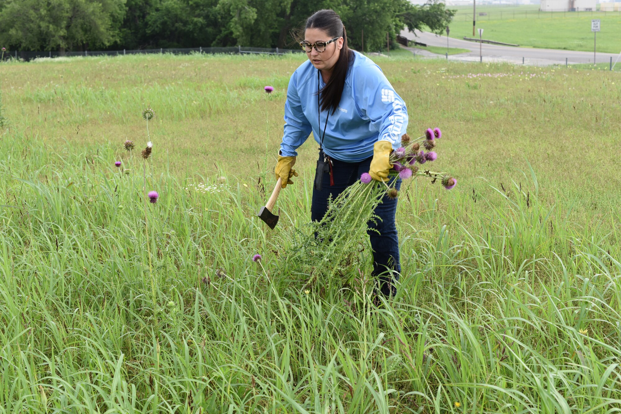 Woman chopping down weeds with hatchet.