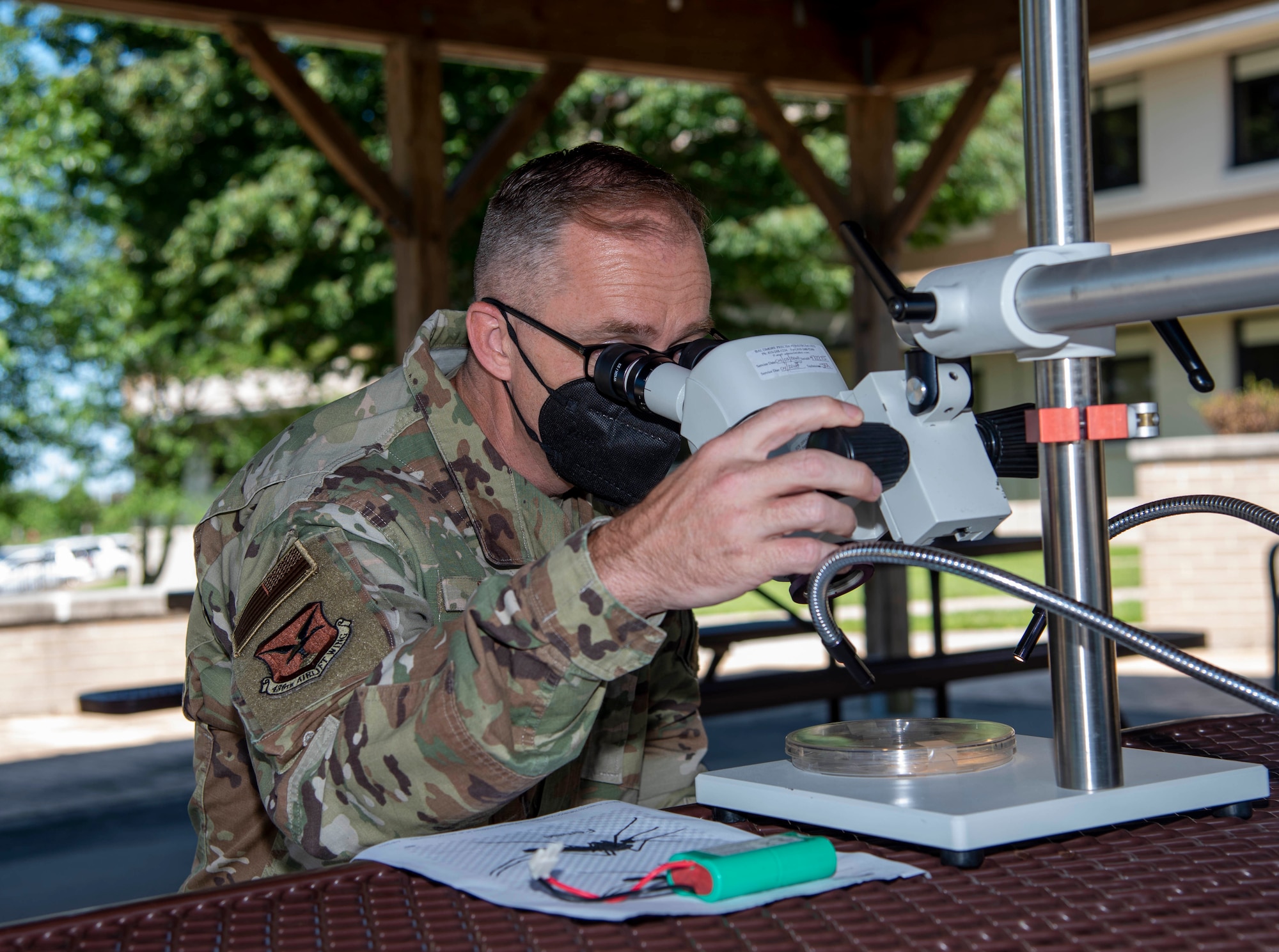 Chief Master Sgt. Timothy Bayes, 436th Airlift Wing command chief, uses a microscope to see male and female mosquitoes during a briefing from 436th Operational Medical Readiness Squadron public health flight Airmen during a 436th Medical Group immersion at Dover Air Force Base, Delaware, June 17, 2021. The immersion gave Bayes hands-on experience of 436th MDG operations. (U.S. Air Force photo by Tech. Sgt. Nicole Leidholm)