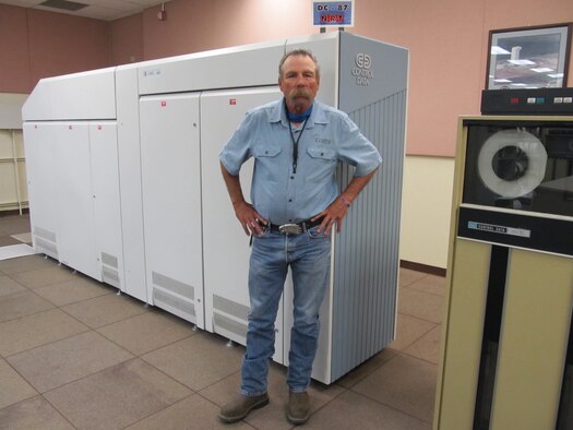 Photo of Dan Nunnelee in front of a "Cyber" mainframe computer