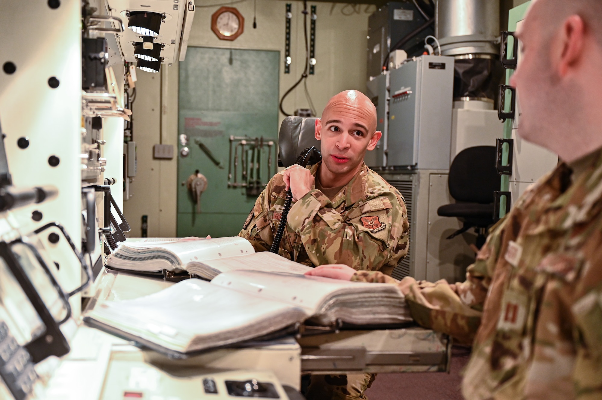 1st Lt. Juan Navarro, 321st Missile Squadron, discusses different actions with Capt. Christian Heath, 321 MS, during training in the Missile Procedures Trainer on F.E. Warren Air Force Base, Wyoming, June 17, 2021. The Air Force Association awarded Heath and Navarro the 2020 Gen. Thomas S. Power Outstanding Missile Crew Award. (U.S. Air Force photo by Joseph Coslett)