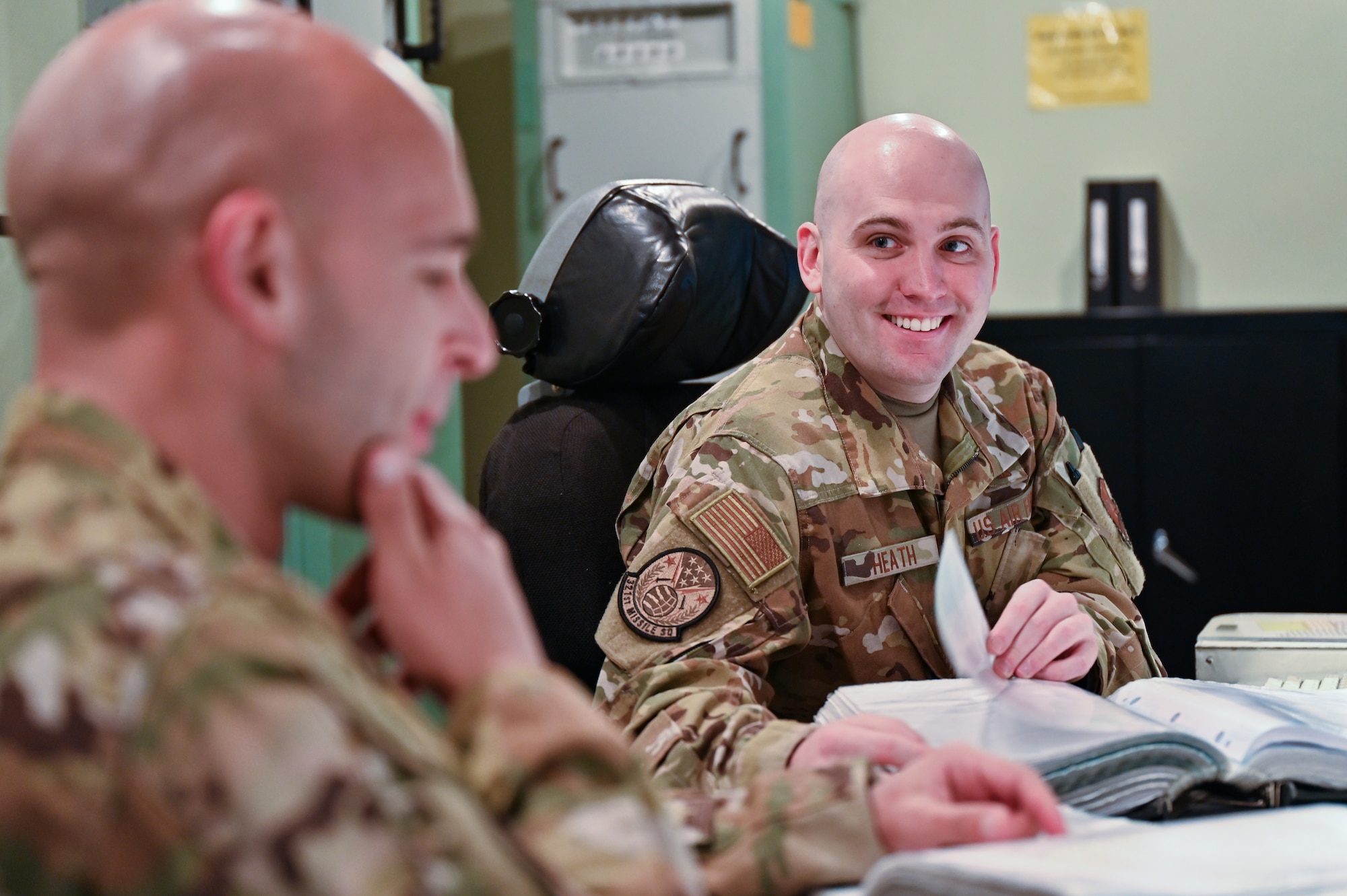 pt. Christian Heath, 321st Missile Squadron, discusses a procedural checklist with 1st Lt. Juan Navarro, 321 MS, during training in the Missile Procedures Trainer on F.E. Warren Air Force Base, Wyoming, June 17, 2021. The Air Force Association awarded Heath and Navarro the 2020 Gen. Thomas S. Power Outstanding Missile Crew Award. (U.S. Air Force photo by Joseph Coslett)