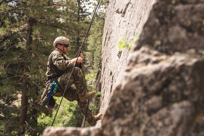 Navy Seaman Kevin Unwin, a corpsman with Headquarters Battalion, 1st Marine Division, ascends a cliff at the Mountain Warfare Training Center, Bridgeport, Calif., June 16, 2021. U.S. Sailors, Soldiers and Marines learned how to use rope systems to transport themselves and patients through technical terrain during the Mountain Medicine Course.