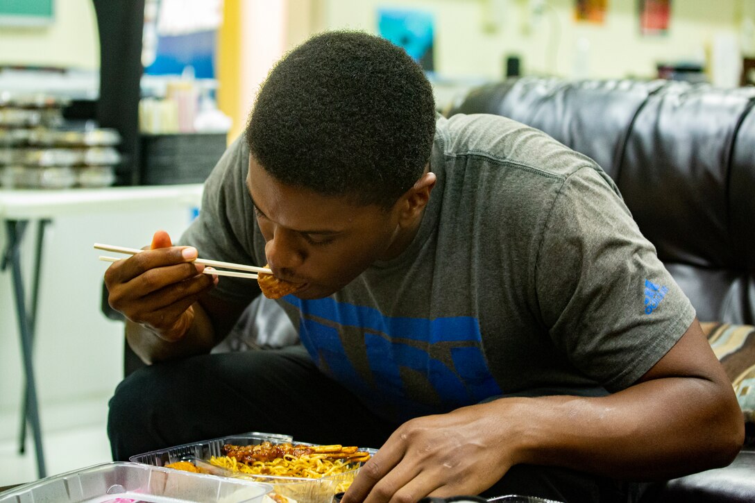 U.S. Navy sailor Petty Officer 3rd Class Micah Marshall, religious program specialist, 3rd Reconnaissance, 3d Marine Division, enjoys Japanese food at the Camp Schwab Single Marine Program Center June 18, 2021 on Camp Schwab, Okinawa, Japan. The Camp Schwab SMP Center provided traditional Japanese food to Single Marines and greenside sailors to celebrate International Sushi Day which is held on the 18th of June to commemorate the Japanese delicacy. The form of sushi containing fish, vegetables, rice and seaweed people enjoy today, originates back to 1600 AD during Japan’s Edo Period.  Marshall is a Pittsburgh, Pennsylvania native. (U.S. Marine Corps photo by Staff Sgt. Lucas Vega)