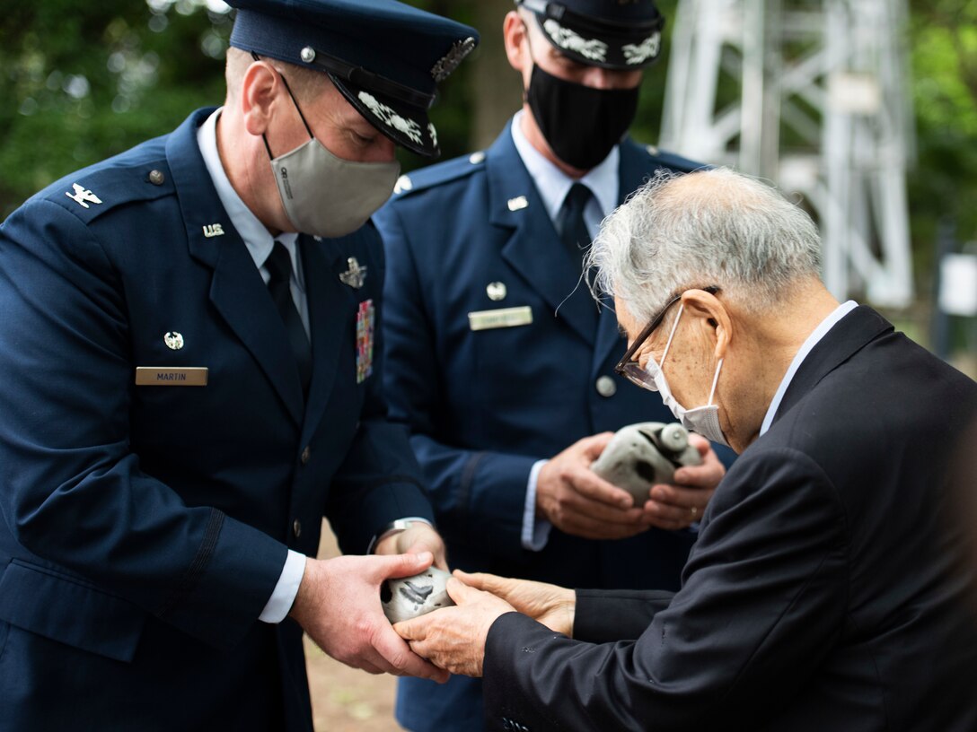 Right, Dr. Hiroya Sugano, memorial ceremony event coordinator, gifts Col. Kevin Martin, 374th Operations Group commander, center, and Col. Andrew Campbell, 374th Airlift Wing commander, with a replica blackened canteen during a memorial ceremony in Shizuoka City, Japan, June 19, 2021. The blackened canteen used during the ceremony is an item that Fukumatsu Itoh, the ceremony’s creator, recovered from one of the B-29 Superfortesses that collided midair during World War II. (U.S. Air Force photo by Staff Sgt. Joshua Edwards)