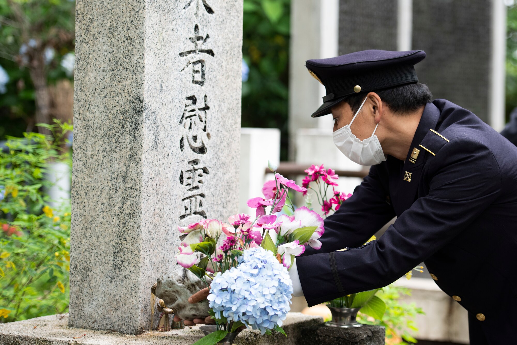 A Japanese Self-Defense Force member pours bourbon on the fallen aircrew memorial during a memorial ceremony in Shizuoka City, Japan, June 19, 2021. Individuals poured bourbon on the memorial to symbolize offering a drink for the fallen service members. (U.S. Air Force photo by Staff Sgt. Joshua Edwards)