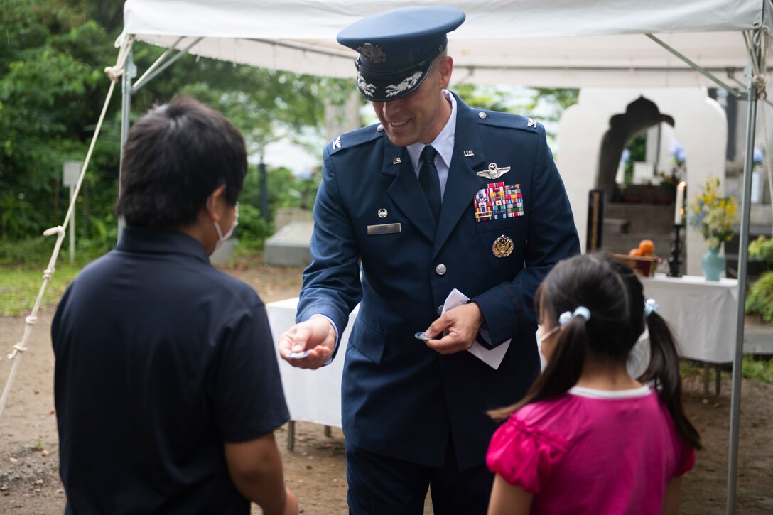 Col. Andrew Campbell, 374th Airlift Wing commander, center, gives a commander’s coin to Ganchi and Motoki Sugano, the grandchildren of the event coordinator, during a memorial ceremony in Shizuoka City, Japan, June 19, 2021. Campbell gifted Sugano’s grandchildren the coin as a symbol of friendship between Japan and the U.S. (U.S. Air Force photo by Staff Sgt. Joshua Edwards)