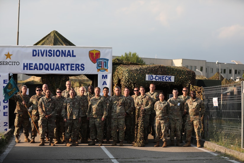 Soldiers of the 2500th Digital Liaison Detachment, 7th Mission Support Command, and the 44th Expeditionary Signal Battalion, 2nd Signal Brigade, along with evaluators from U.S. Army Southern European Task Force-Africa, pose together in front of the divisional operations center of the Italian Army´s Divisione Acqui at the conclusion of a command post exercise for DEFENDER-Europe 21 in Capua, Italy, June 14, 2021. The 2500th DLD provided liaison capability between the U.S. Army´s V Corps and the Italian Army's Divisione Acqui.