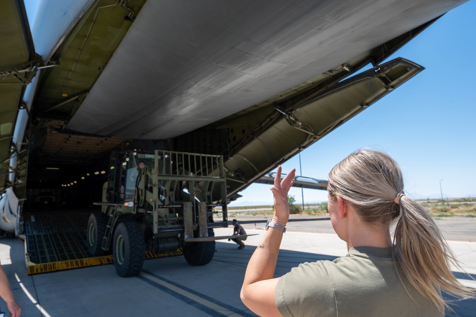 Airman 1st Class Rebecca Reimer, 9th Airlift Squadron loadmaster student, marshals a forklift tractor off the ramp of a Dover Air Force Base C-5M Super Galaxy during a Major Command Service Tail Trainer at Holloman AFB, New Mexico, June 7, 2021. Following an initiative from Air Mobility Command, MSTTs have been in the training plan of the 9th AS since early 2021 to expedite upgrade and qualification training for C-5M Super Galaxy loadmasters and flight engineers. This MSTT was coordinated in partnership with Air Education Training Command’s 49th Wing and Air Force Materiel Command’s 635th Materiel Maintenance Group. (U.S. Air Force photo by Senior Airman Faith Schaefer)