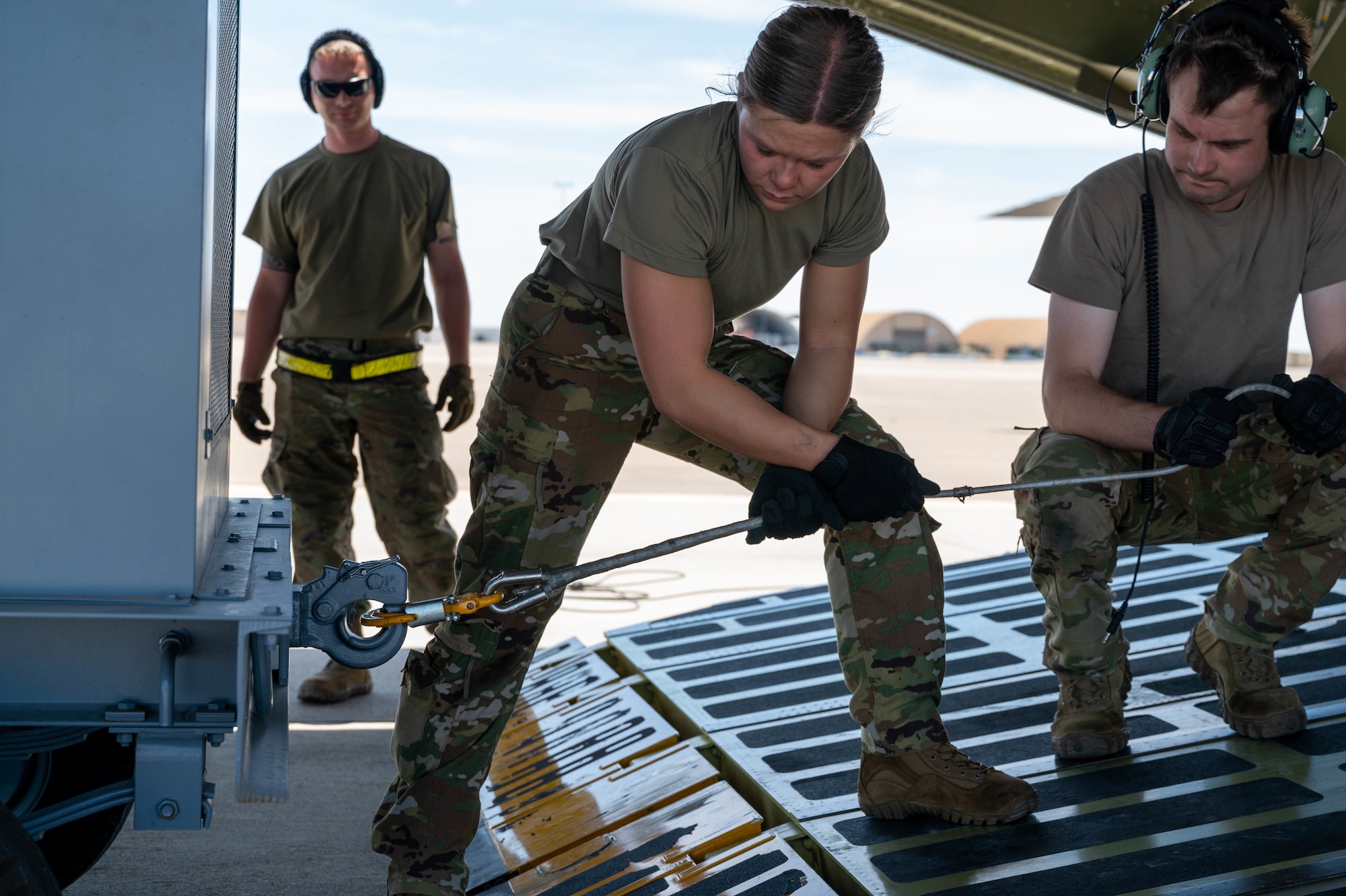 Airman 1st Class Rebecca Reimer, center, 9th Airlift Squadron student loadmaster, and Staff Sgt. John Dittess, right, 9th AS loadmaster, attach a winch to aircraft ground equipment before loading it onto a Dover Air Force Base C-5M Super Galaxy during a Major Command Service Tail Trainer, at Holloman AFB, June 8, 2021. Loadmasters from the 9th AS coordinated cargo with Airmen from Air Education and Training Command’s 49th Wing and Air Force Materiel Command’s 635th Materiel Maintenance Group to complete the 10-day MSTT. Over the course of the training, Airmen loaded and unloaded 320,085 pounds of cargo, including palletized cargo, AGE, a fuel truck and a K-loader. (U.S. Air Force photo by Senior Airman Faith Schaefer)