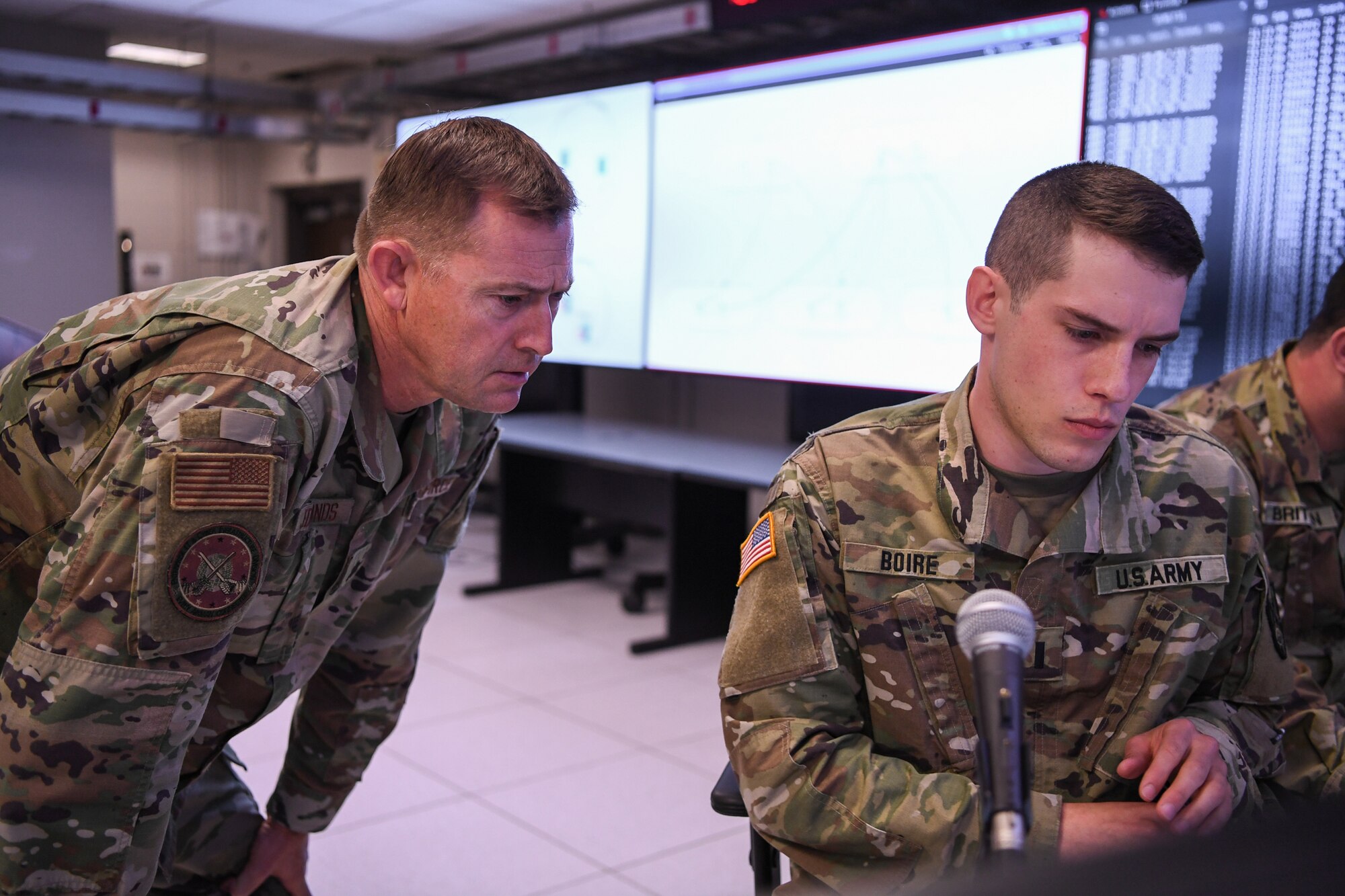 Lt. Col. Darren Edmonds, director of the Lantern, also known as the Hanscom Collaboration and Innovation Center, looks on as 1st Lt. Nicholas Boire, from the Massachusetts National Guard’s 126th Cyber Protection Battalion, reviews data during a proof of concept event at Hanscom Air Force Base, Mass., May 20.
