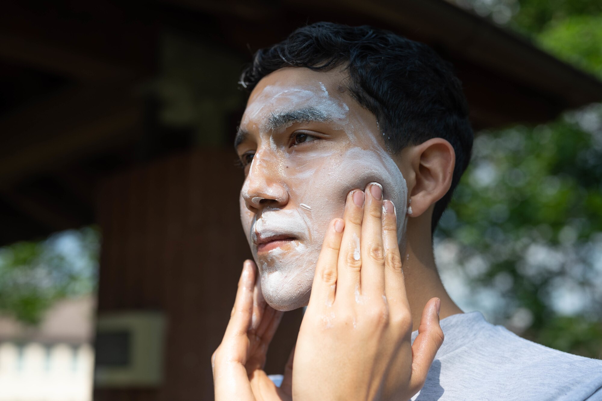 Young Airman applies too much sunscreen to face.