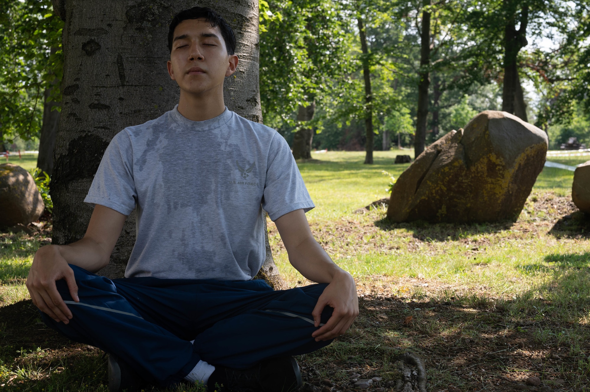 Young man meditating under a tree.