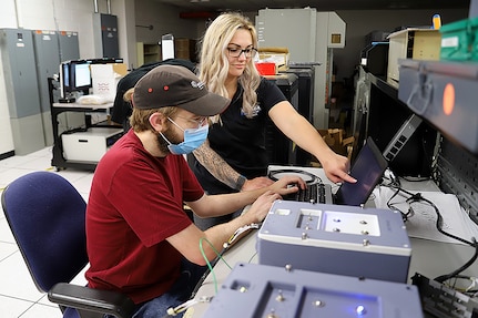 IMAGE: Lauren Sencio, Ship Self Defense System Hardware Design Task Planning Lead, and Kevin Newcomer, an SSDS Hardware Design Team computer engineer, test a 3D-printed arming unit May 25, at Naval Surface Warfare Center Dahlgren Division Dam Neck Activity in Virginia Beach, Virginia. The SSDS Hardware Design Team worked with DNA’s FIRE Lab to 3D print the arming unit—a component of the SSDS Command Control Group console—to speed up design validation for the prototype.