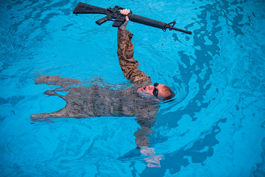 Navy Petty Officer 2nd Class Christopher Walters, a hospital corpsman with 3rd Medical Battalion, 3rd Marine Logistics Group, conducts a rifle swim during the water survival advanced course on Marine Corps Air Station Futenma, Okinawa, Japan, June 17, 2021. WSA is the highest swim qualification Marines and sailors can obtain before moving onto the next echelon of becoming a Marine Corps Instructor of Water Survival. The week-long course kicks off with a water survival pre screening event, and the remainder of the course consists of numerous endurance swims, life-saving techniques and applications, physical and mental conditioning, and countless swimming drills to ensure students have the confidence to not only maintain themselves but others’ lives while in the water. Walters is a native of Upland, California.