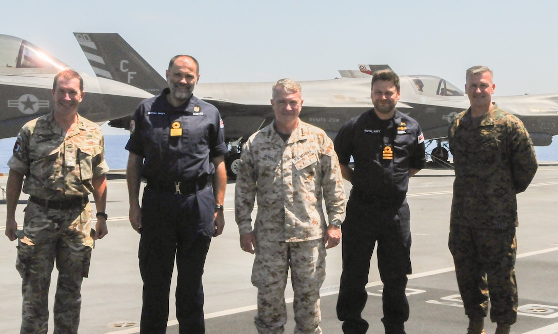 SICILY, Italy–  Gen. Kenneth McKenzie, commander, U.S. Central Command, center, poses for a photo with United Kingdom Carrier Strike Group leaders aboard HMS Queen Elizabeth June 14, 2021. Gen. McKenzie boarded the British Royal Navy ship from the Port of Augusta, the first in a series of port visits en route to the Mediterranean for the HMS Queen Elizabeth’s first operational deployment. The aircraft carrier launches F-35B Joint Strike Fighters operated and maintained by U.S. and British servicemembers.