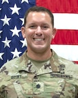 photo of a man in front of a flag.