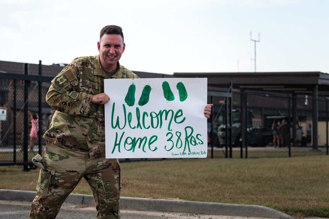 A photo of an Airman holding a Welcome Home sign