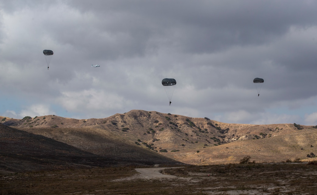 U.S. Marines parachute down to Drop Zone Basilone during a parachute operation on Marine Corps Base Camp Pendleton, California, Dec. 10, 2020. Marines with Air Delivery Platoon, Landing Support Company, 1st Transportation Support Battalion, 1st Marine Logistics Group, coordinated the training opportunity to support various units around the base and enable Marines to gain proficiency and remain current with their airborne jump training. (U.S. Marine Corps Photo by Lance Cpl. Andrew Cortez)