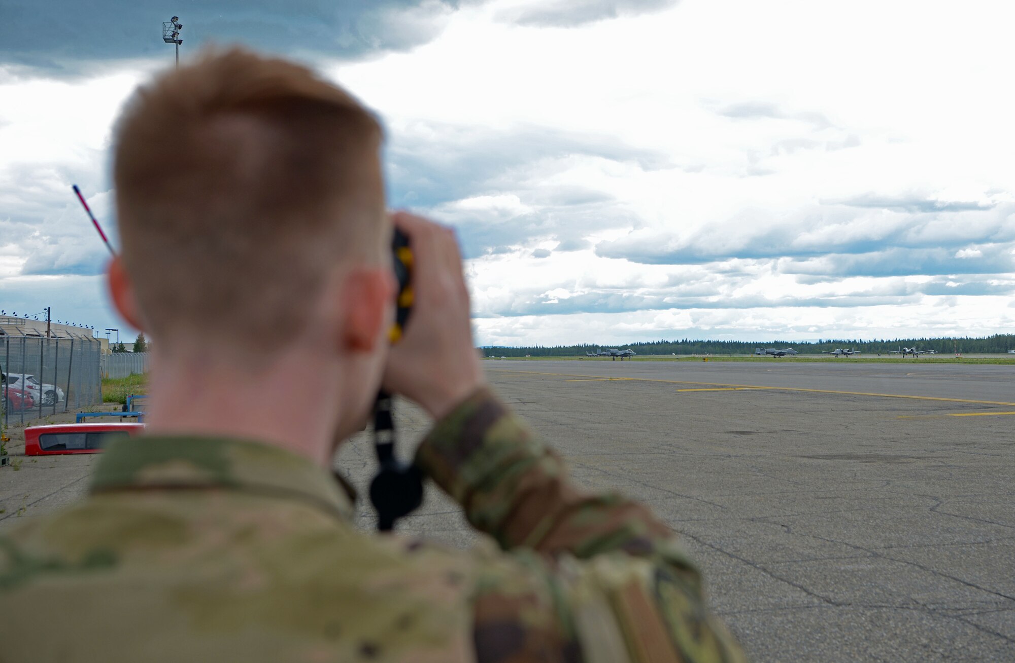 U.S. Air Force Senior Airman Zachary Rodgers, 354th Operations Support Squadron Airfield Management Flight shift lead, watches for wildlife while A-10 Thunderbolt IIs take off during RED FLAG-Alaska 21-2 on Eielson Air Force Base, Alaska, June 21, 2021. Rodgers and his team work with many different units to ensure the airfield is clear of animals and the lights are functioning properly. (U.S. Air Force photo by Senior Airman Beaux Hebert)