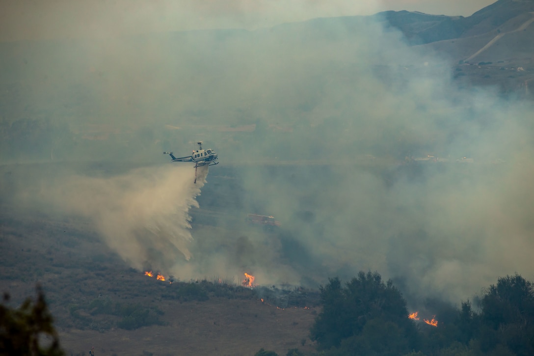 A San Diego Sheriff Bell 205 A1 fire and rescue helicopter drops water in an effort to extinguish the Creek Fire aboard Marine Corps Base Camp Pendleton, California, Dec. 24, 2020. Camp Pendleton Fire Department and Cal Fire San Diego are in a unified command to battle the 3,000 acre fire. (U.S. Marine Corps photo by Lance Cpl. Kerstin Roberts)