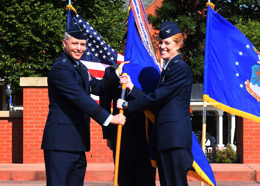 Uniformed male hands unit flag to uniformed female.