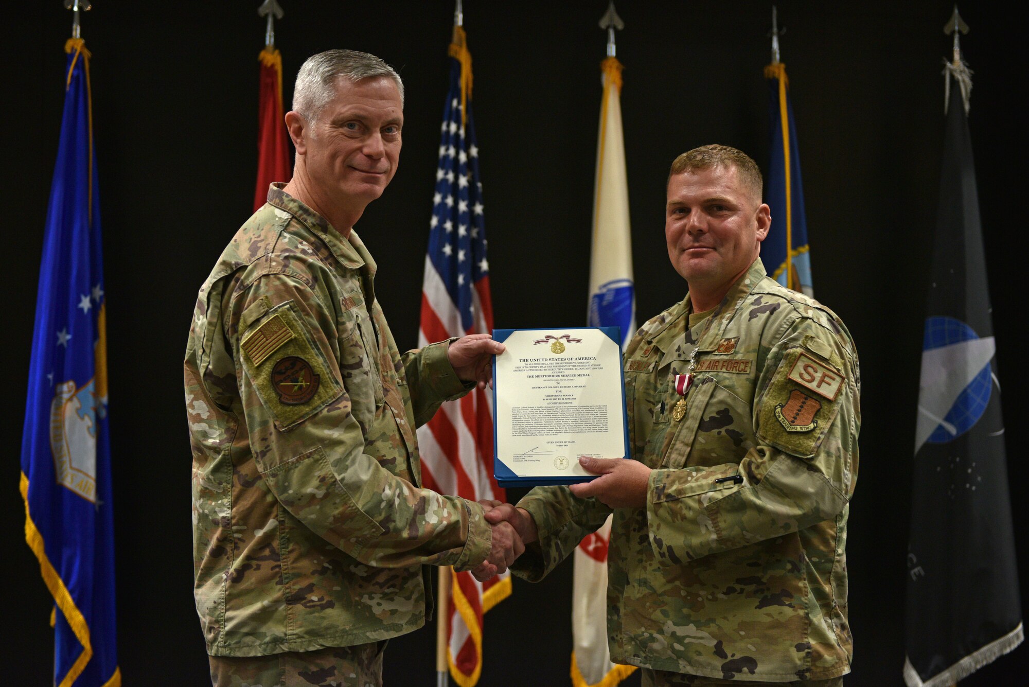 U.S. Air Force Col. Tony England, 17th Mission Support Group commander, presents Lt. Col. Richard Buckley, outgoing 17th Security Forces Squadron commander, the Meritorious Service Medal during the change of command ceremony at the Event Center on Goodfellow Air Force Base, Texas, June 22, 2021. Buckley was decorated for his performance and leadership of the 17th SFS, which led to numerous annual awards and a Major Command Award. (U.S. Air Force photo by Senior Airman Ashley Thrash)
