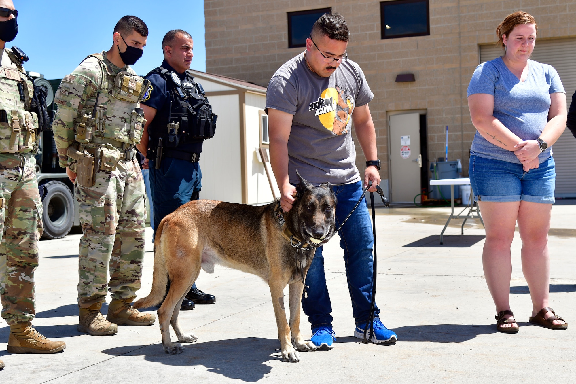 Staff Sgt Reyes pets retired military working dog Cvoky as others look on in the background.