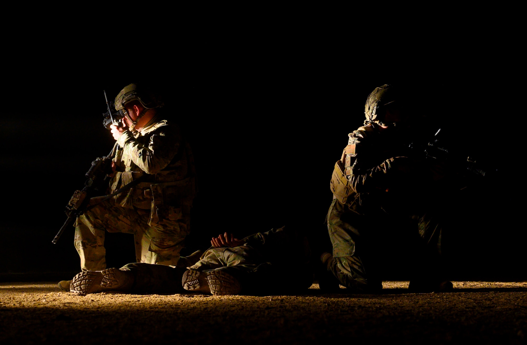 U.S. Air Force defenders with the 378th Expeditionary Security Forces Squadron guard a simulated subdued enemy participant a quick response training event in blackout conditions at Prince Sultan Air Base, Kingdom of Saudi Arabia, June 12, 2021. PSAB Explosive Ordnance Disposal, Security Forces and Medical personnel participated in integrated training to bolster defensive capabilities and maintain readiness at all times. (U.S. Air Force Photo by Senior Airman Samuel Earick)