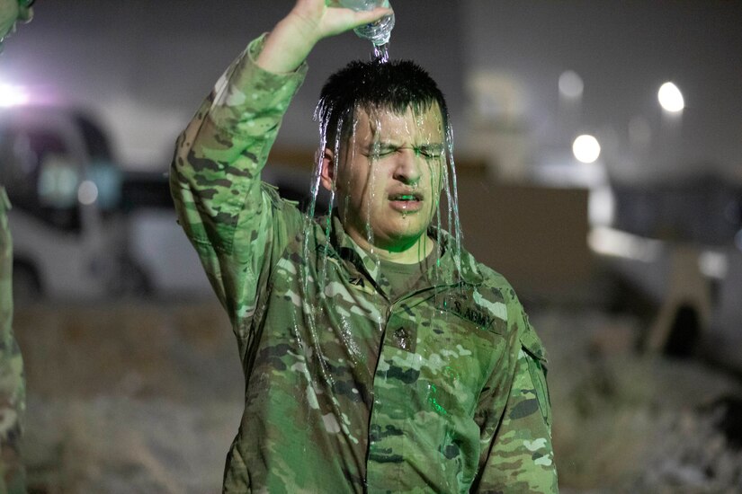 U.S. Army Pfc. Francisco Espinoza, a human resource specialist with 160th Signal Brigade, pours cold water over his head upon completing an 8-mile ruck march during the U.S. Army Central 2021 Best Warrior Competition at Camp Arifjan, Kuwait, June 22, 2021. Competitors completed the ruck in temperatures over 100 degree Fahrenheit. (U.S. Army photo by Spc. Elizabeth Hackbarth, U.S. Army Central Public Affairs)