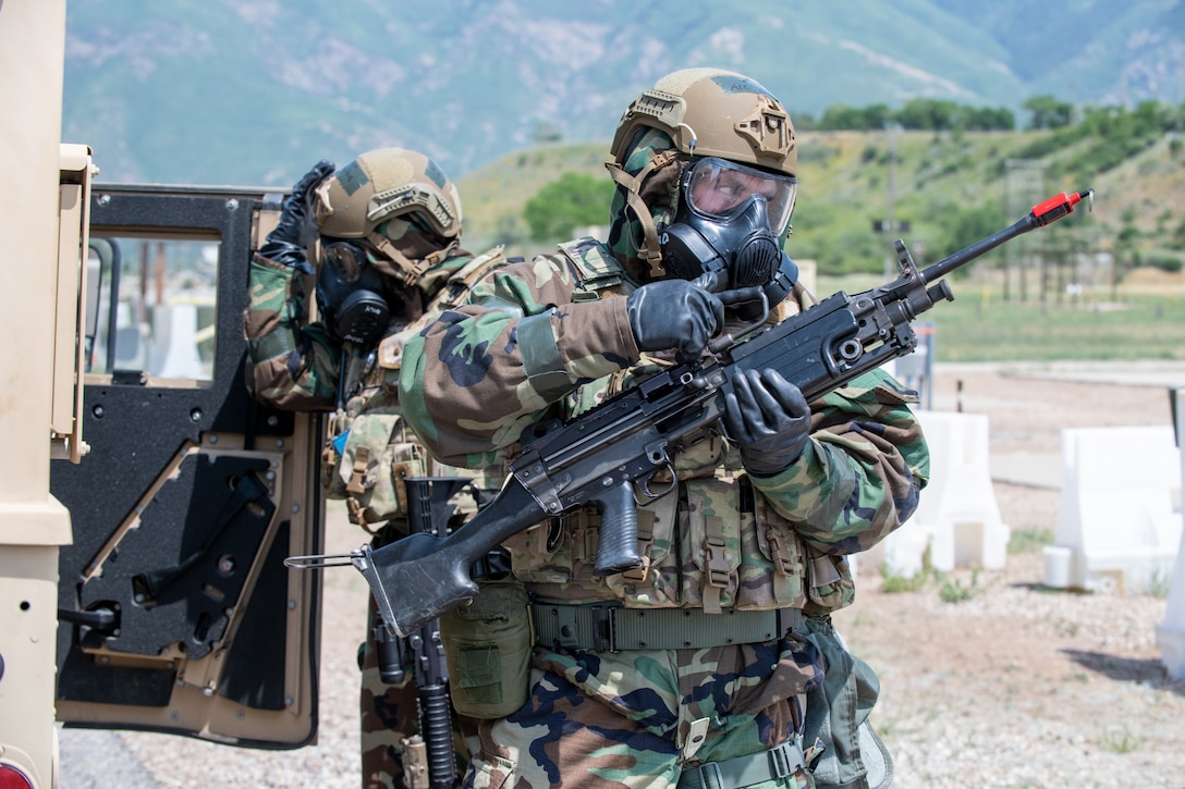 An Airmen holding a rifle and dressed in chemical gear.