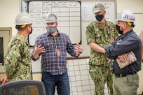 Rear Admiral Jeffrey Jablon, commander, Submarine Force, U.S. Pacific Fleet, is briefed on process improvements by Matt VanRavenhorst, NSS-SY champion, middle left, and Dan Arnell, Shop 31 production superintendent, right, June 8, 2021, during a tour of Puget Sound Naval Shipyard & Intermediate Maintenance Facility in Bremerton, Washington. (PSNS & IMF photo by Scott Hansen)