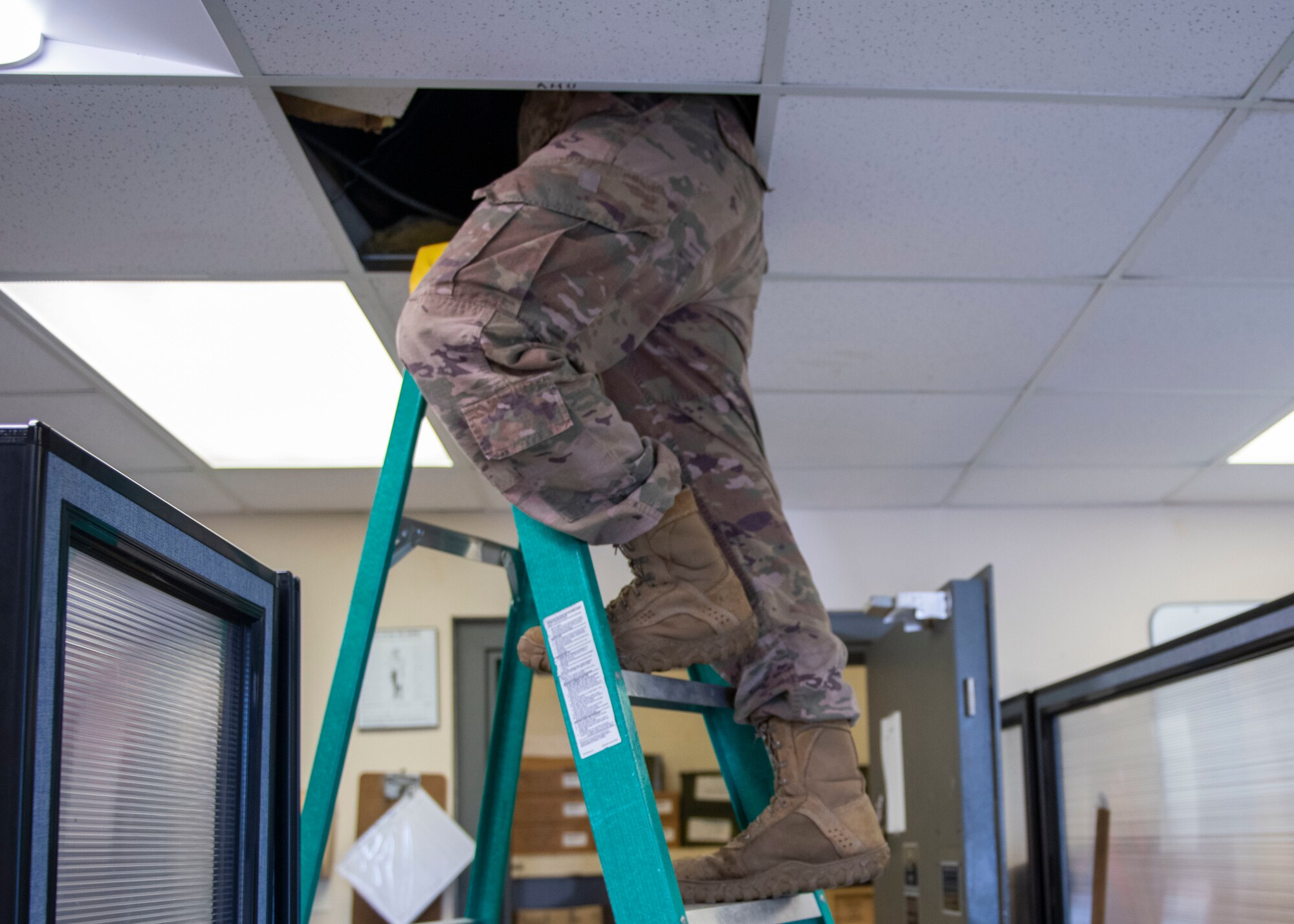 Staff Sgt. Mitchell Cole, 4th Civil Engineer Squadron heating, ventilation, air conditioning and refrigeration technician, climbs into a drop ceiling to access an indoor air conditioning unit at Seymour Johnson Air Force Base, North Carolina, June 14, 2021.