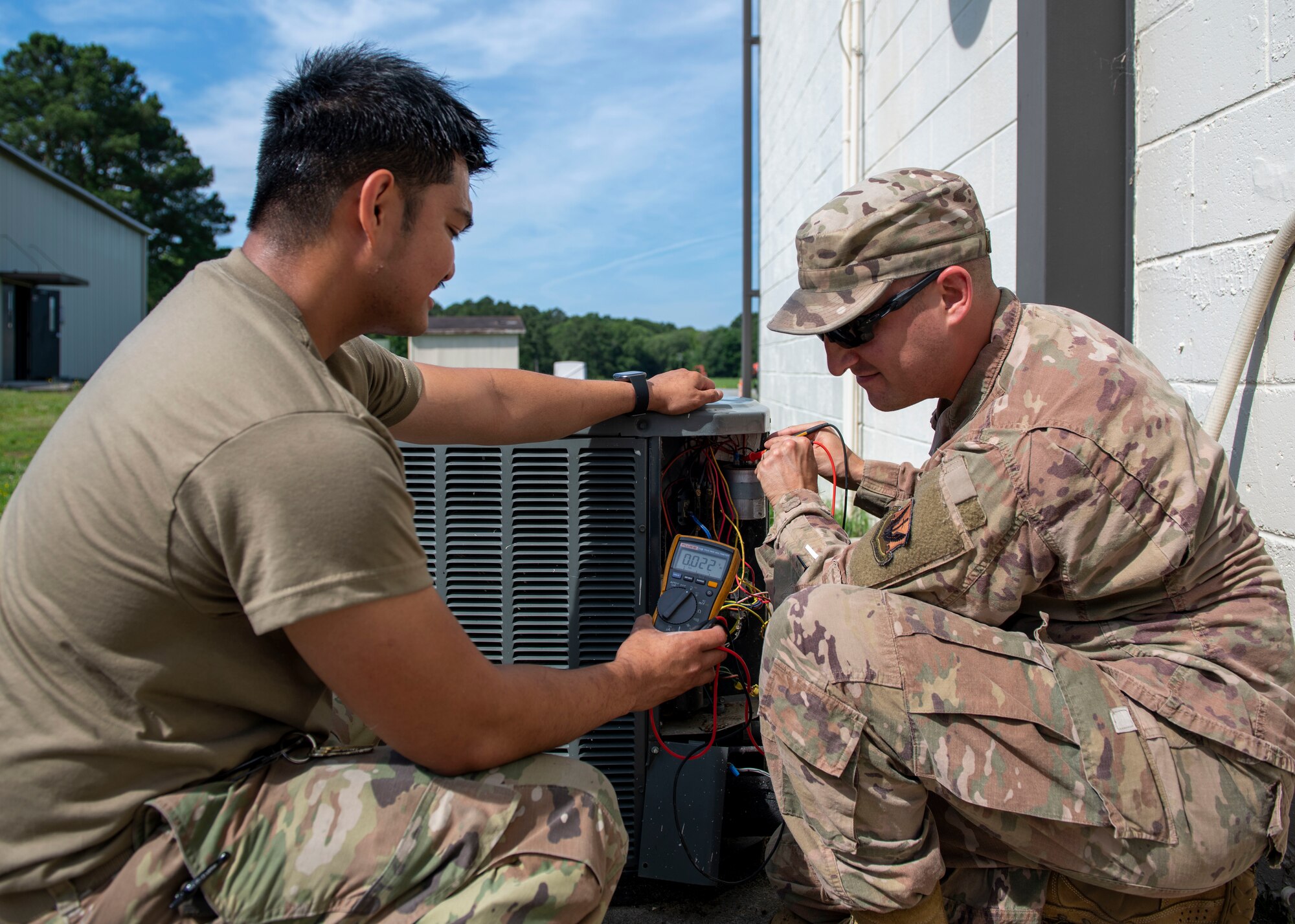 Senior Airman Joje Masaganda, left, and Staff Sgt. Mitchell Cole, 4th Civil Engineer Squadron heating, ventilation, air conditioning and refrigeration technicians, use a multimeter to check components of a split system air conditioning unit for power loss at Seymour Johnson Air Force Base, North Carolina, June 14, 2021.