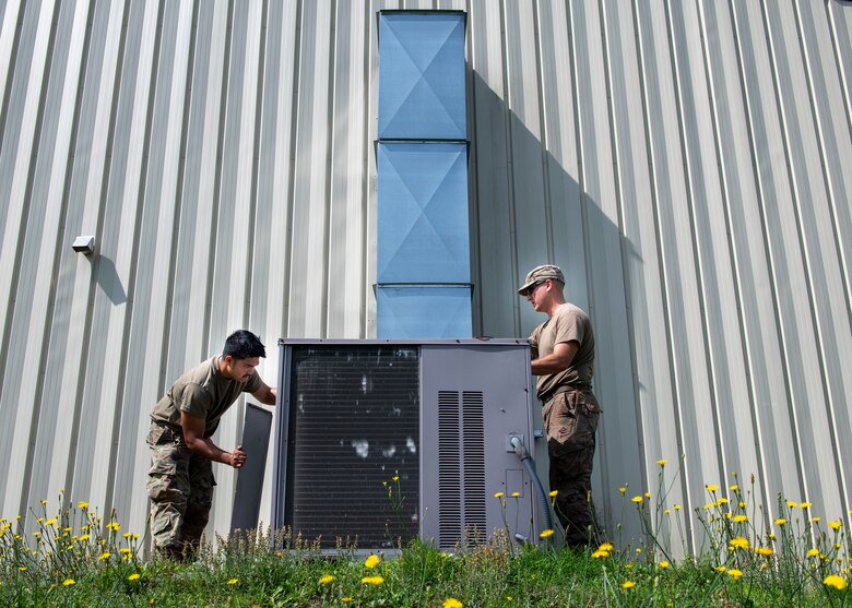 Senior Airman Joje Masaganda, left, and Staff Sgt. Mitchell Cole, 4th Civil Engineer Squadron heating, ventilation, air conditioning and refrigeration technicians, remove panels from an air conditioning package unit at Seymour Johnson Air Force Base, North Carolina, June 14, 2021.