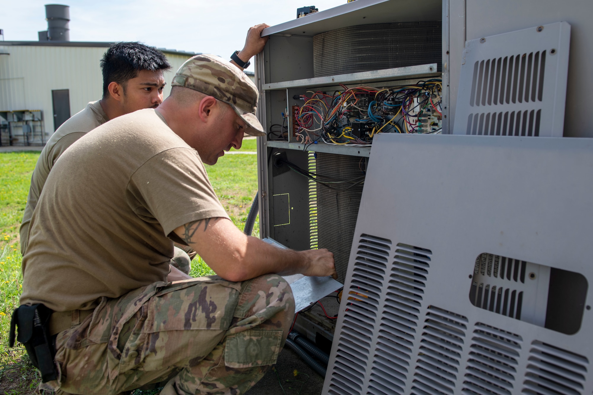 Senior Airman Joje Masaganda, left, and Staff Sgt. Mitchell Cole, 4th Civil Engineer Squadron heating, ventilation, air conditioning and refrigeration technicians, use a schematic to figure out which component of an air conditioning package unit was not functioning at Seymour Johnson Air Force Base, North Carolina, June 14, 2021.